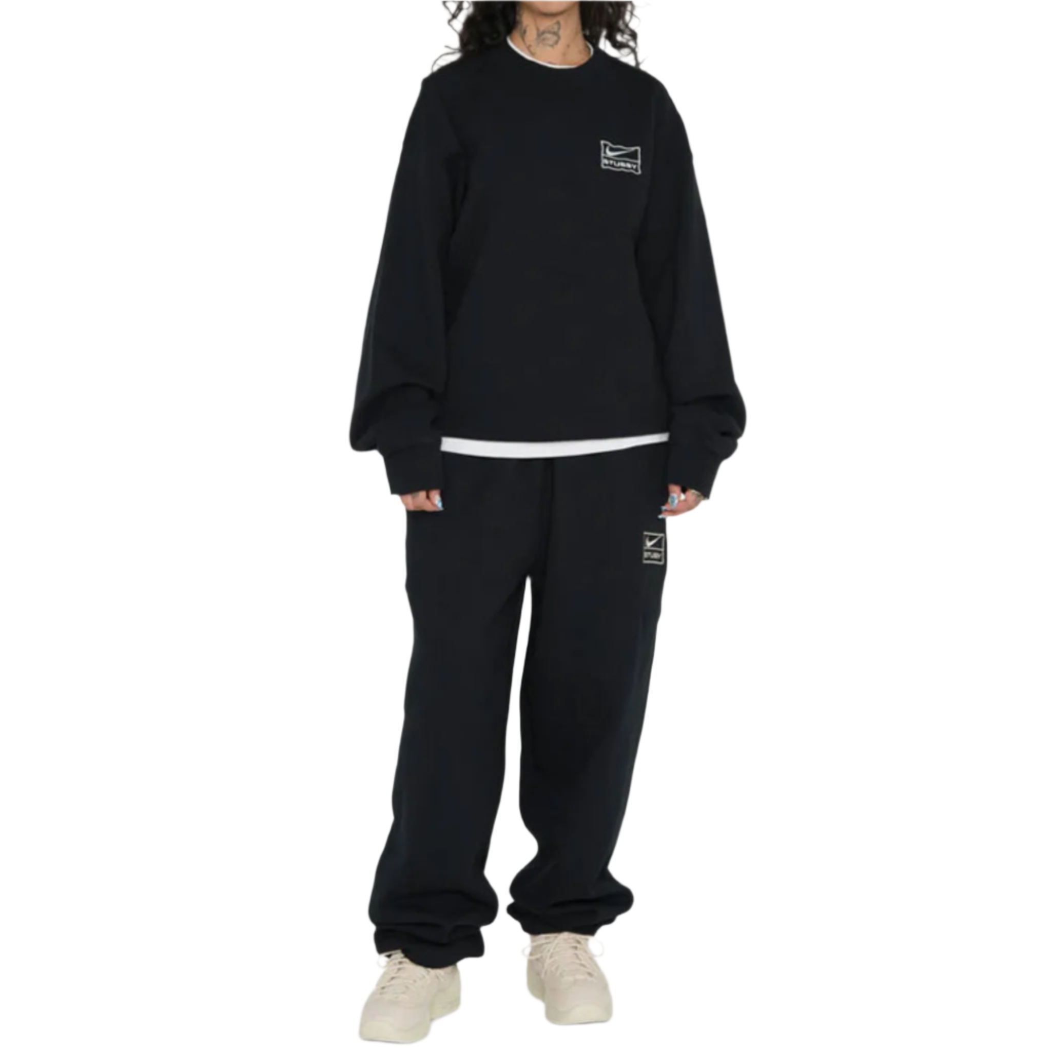 Person wearing a black sweatshirt and pants with logos on a white background
